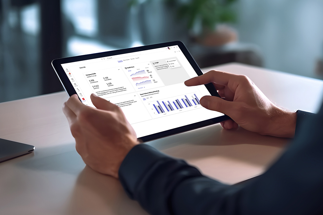 A person holding a tablet in an office setting viewing a financial dashboard with various data visualizations.